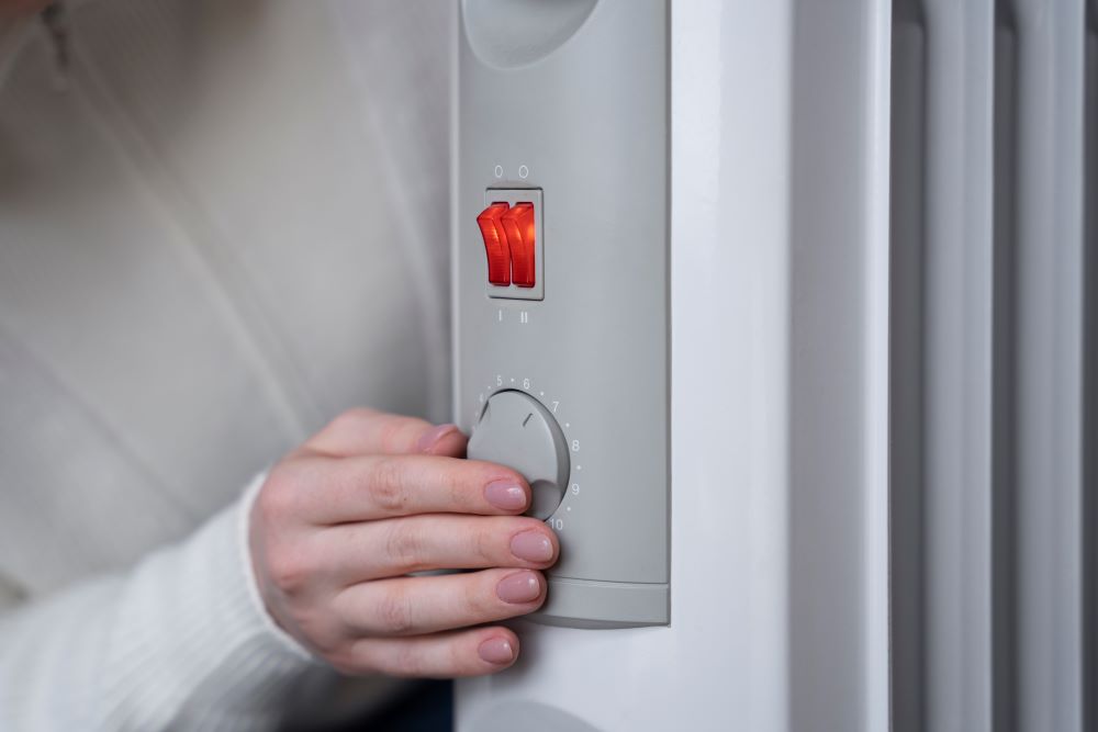 Une personne s'apprête à allumer son système de chauffage hydronique grâce à une centrale de contrôle et d'ajustement de la température.